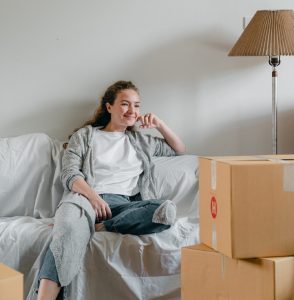 Lady sitting on a couch smiling after packing items into boxes