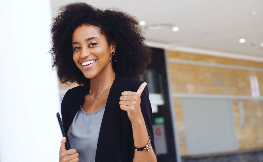 Portrait of a confident young businesswoman showing a thumbs up gesture in a modern office