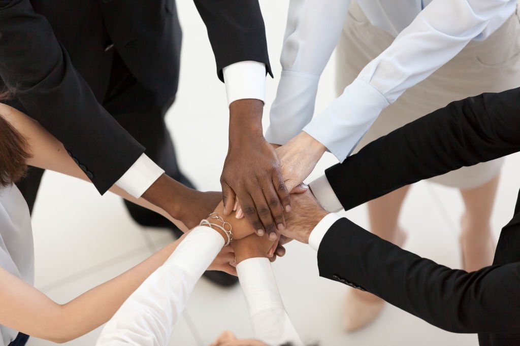 Diverse business people group put hands together in stack pile at training as concept of sales team corporate unity connection, teambuilding loyalty, support in teamwork, coaching, close up top view