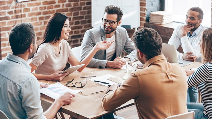 6 corporate people sitting at a table smiling and chatting