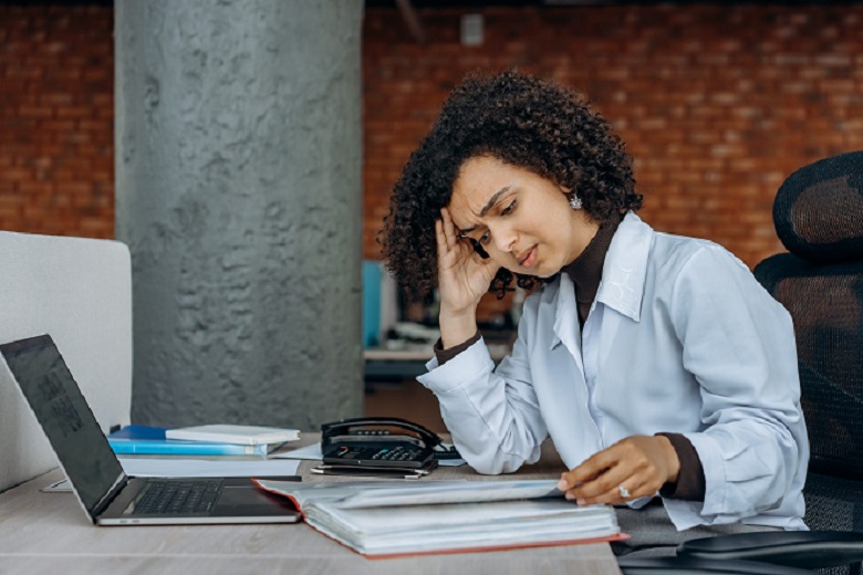 A women with curly hair looking stressed while reading at work