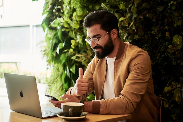 A man at a café smiling and looking at his phone