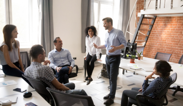 Confident male leader, coach talking with group of office workers